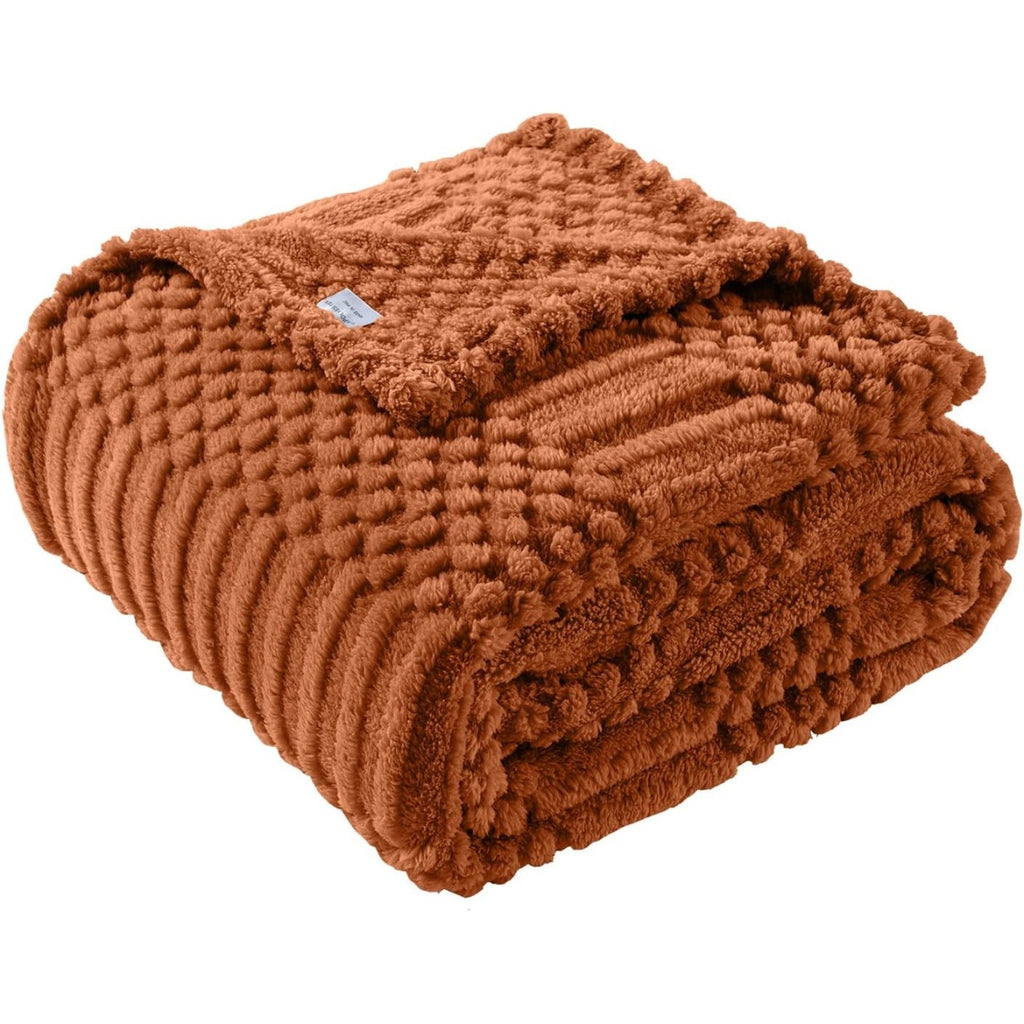 Rust colored fleece throw blanket folded on a sofa