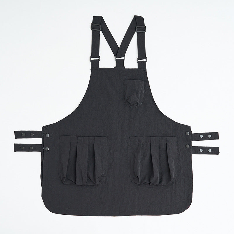 Black kitchen apron shown flat with adjustable waist ties