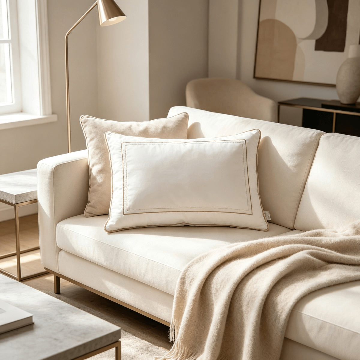 White hotel pillows arranged on a cream sofa with a knitted throw