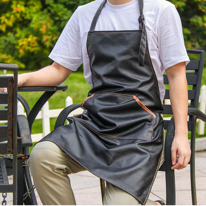 Craftsman seated wearing a black leather work apron with chest pocket