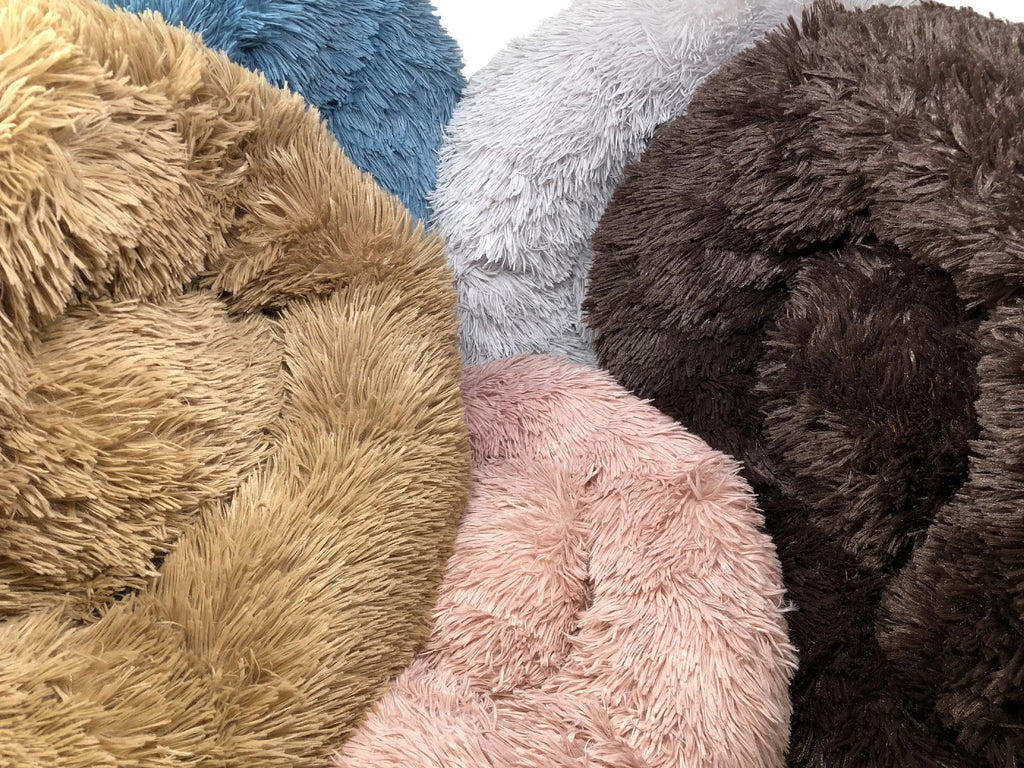 Four plush round dog beds in khaki, blue, pink and brown